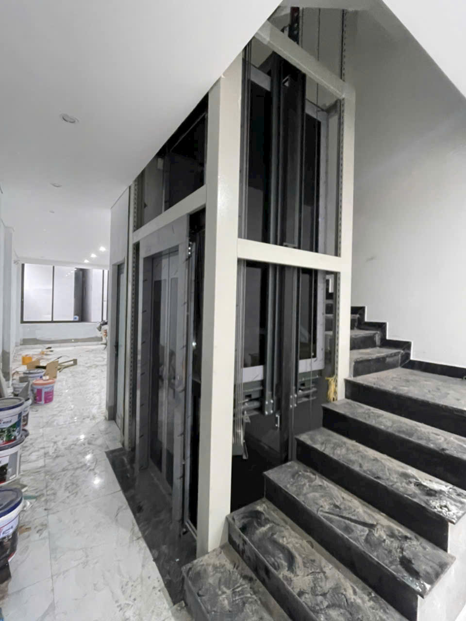 Thang máy gia đình đang lắp đặt cạnh cầu thang trong ngôi nhà đang hoàn thiện